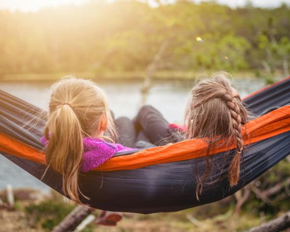 two sisters sit on a hammock.
