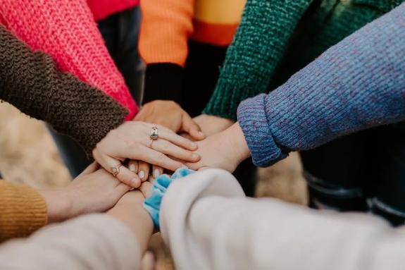 Group of people placing hands in a circle to symbolise togetherness